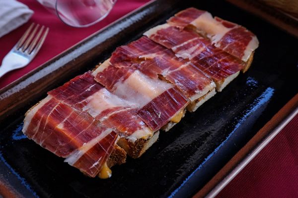 Platter of Iberian cured ham from acorn-fed pigs served with fresh tomatoes or Salmorejo (chilled tomato purée made with tomato, olive oil, and bread)